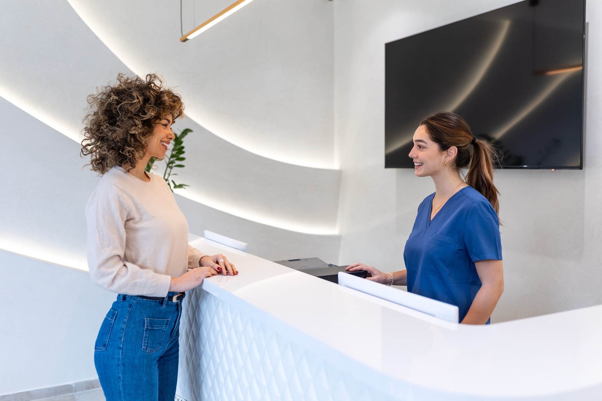 Patient warmly welcomed by a front-desk staff member at a medical practice