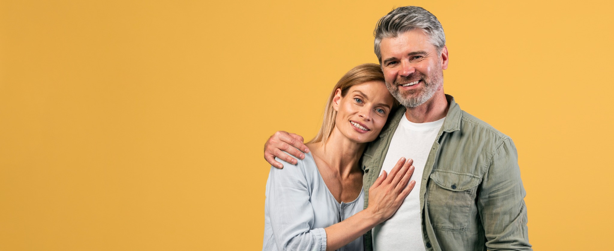 Smiling couple embracing against a yellow background